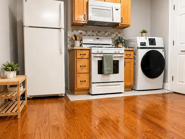 Efficient kitchen setup with full-size refrigerator, range with microwave, ample cabinetry, and in-unit laundry nearby.