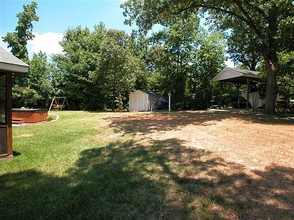 Fenced, wooded back yard features storage shed