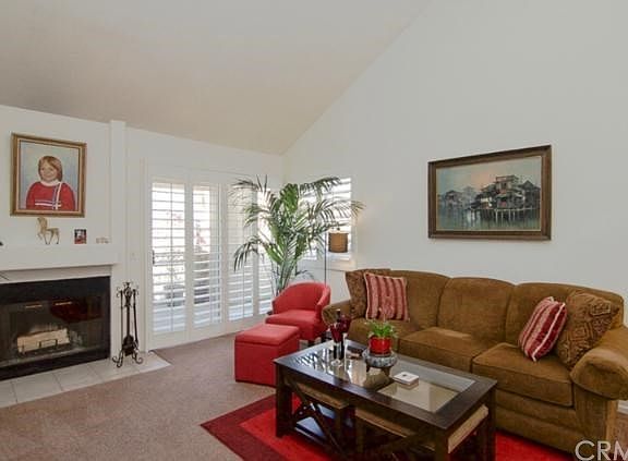 This large living room features tall cathedral ceilings, wood burning fireplace, and direct access to the balcony.