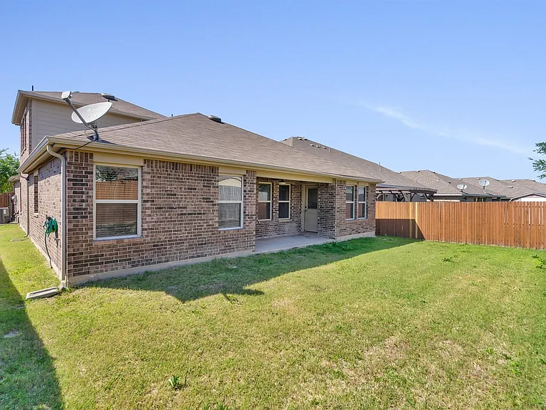 Expansive backyard featuring a manicured lawn, full privacy fencing, and a concrete patio