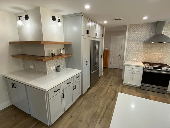 Quartz countertops, large coffee bar, floating shelves, two tone cabinets and a stainless steel refrigerator flush with spacious pantry cabinets.