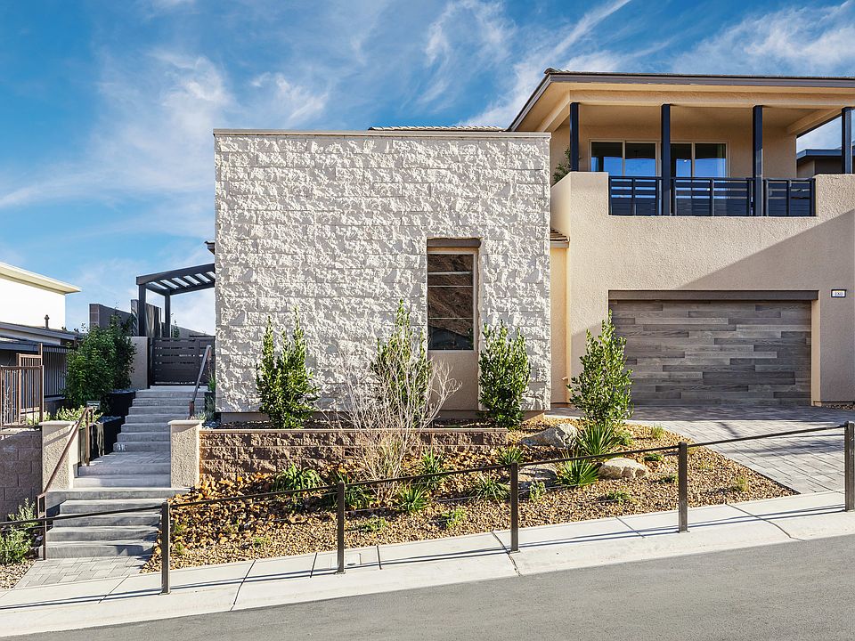 A modern, two-story residential building with a stone facade, a garage, and a landscaped front yard