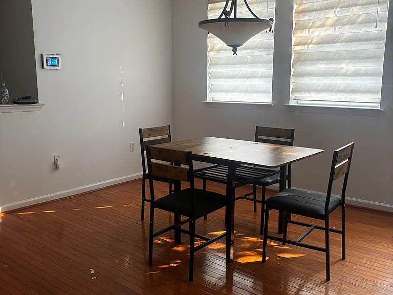 Dedicated dining area with hardwood floors, pendant lighting, and two windows with shades for comfortable everyday meals.