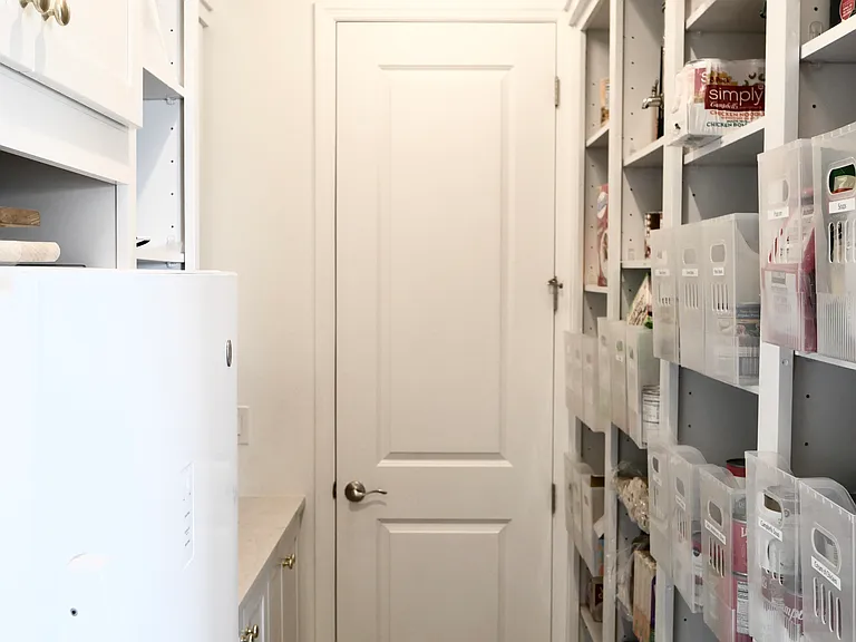 Walk in pantry with extra freezer, storage, appliance shelves.