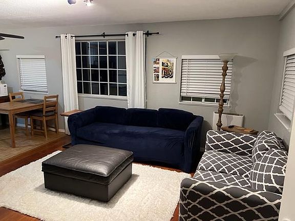 Living room area. Newly installed heater on the wall and Bluetooth speaker in coffee table. Charging station is on another side table next to blue couch.