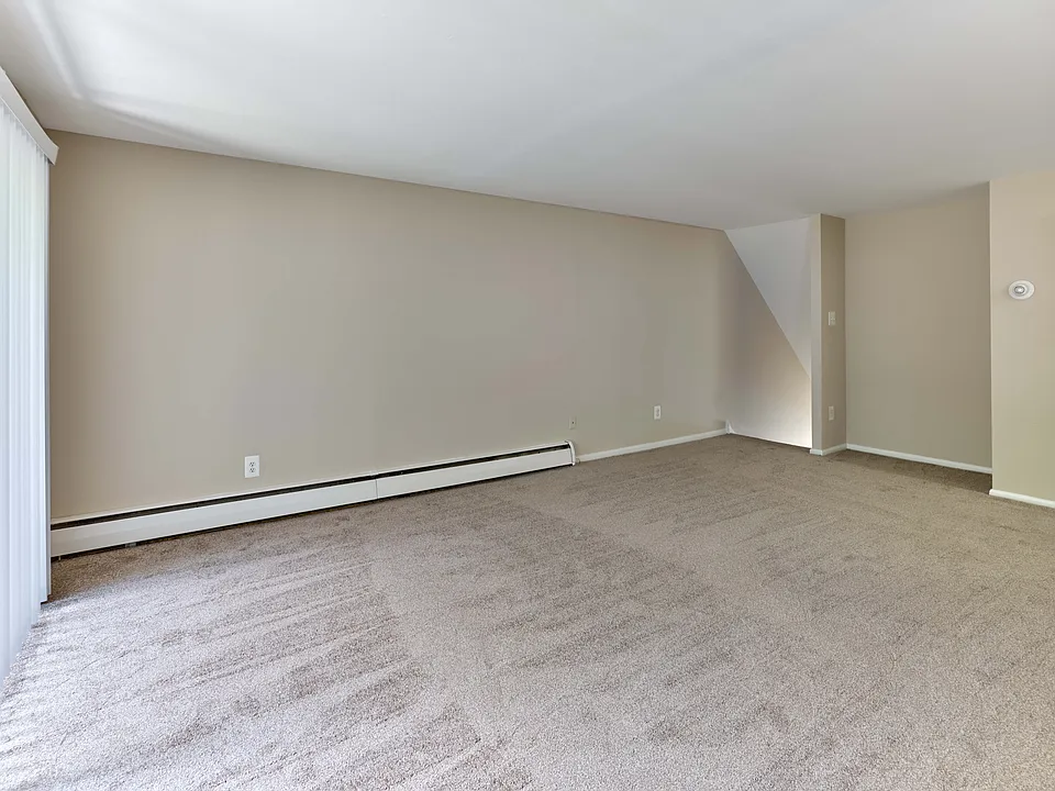 Spacious living room with plush carpet and open layout at Maple Terrace Apartments in Maple Shade, NJ