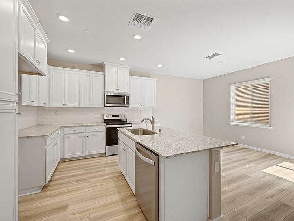 The kitchen has a huge kitchen island and stainless steel appliances.