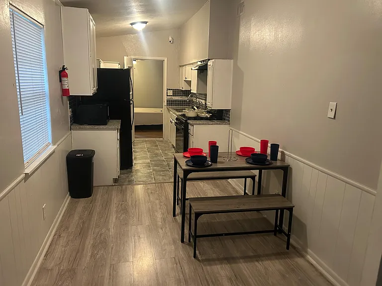 Galley kitchen with ample cabinetry, full-size appliances, and an eat-in table; open sightline to the adjacent bath.