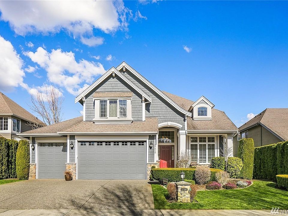 Street view of property featuring the 3 car garage and beautiful landscaping