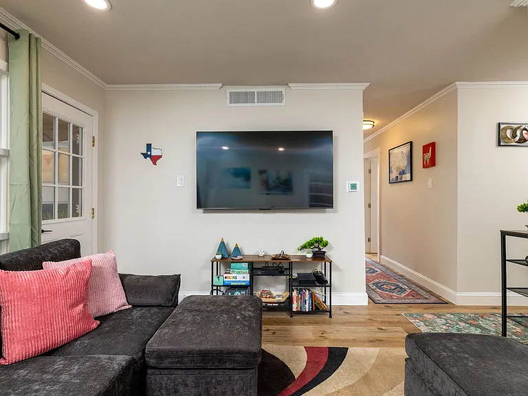 Bright, cozy living room with a large sectional, modern art, big windows, a smart TV, board games, and a DVD collection. Perfect for relaxing, gathering, or getting work done in a stylish, welcoming space.