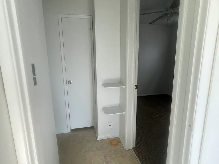 Hallway from living room to bedroom on the right and bathroom on the left