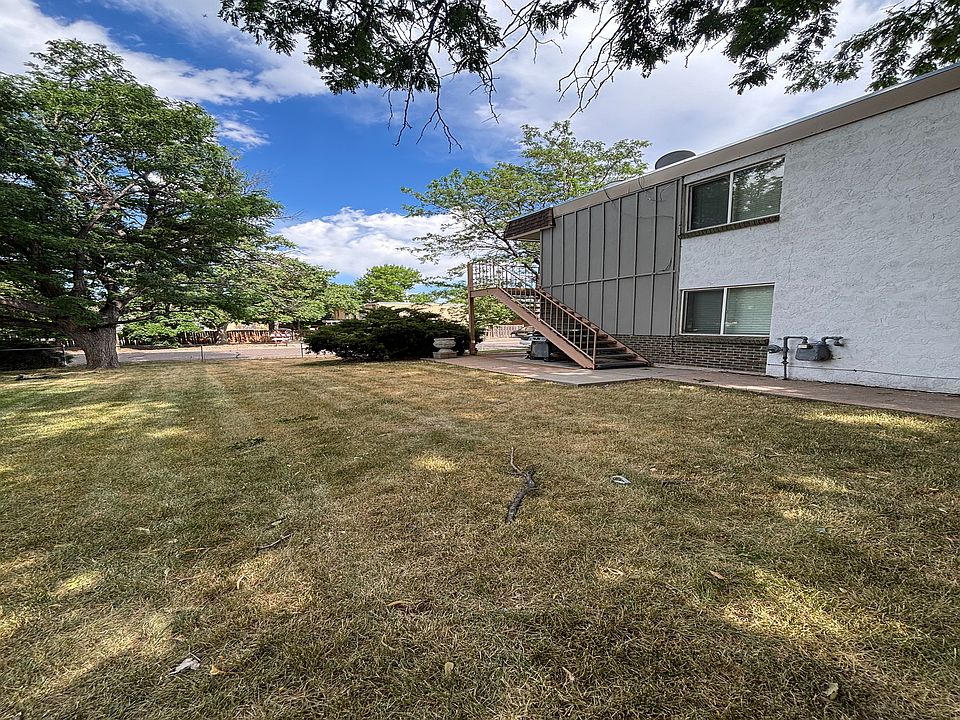 Charming apartment exterior with lush green lawn and mature trees, offering serene outdoor space and scenic views.