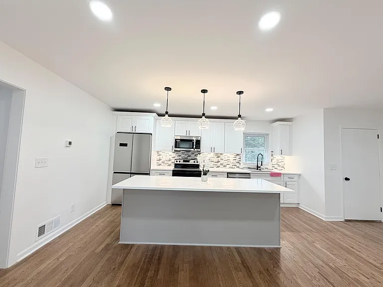 Spacious kitchen with large island, shaker cabinetry, stainless appliances, and pendant lighting for easy meal prep.
