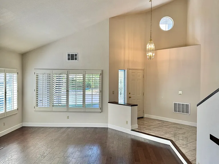 Living room and entry featuring high ceilings and window shutters