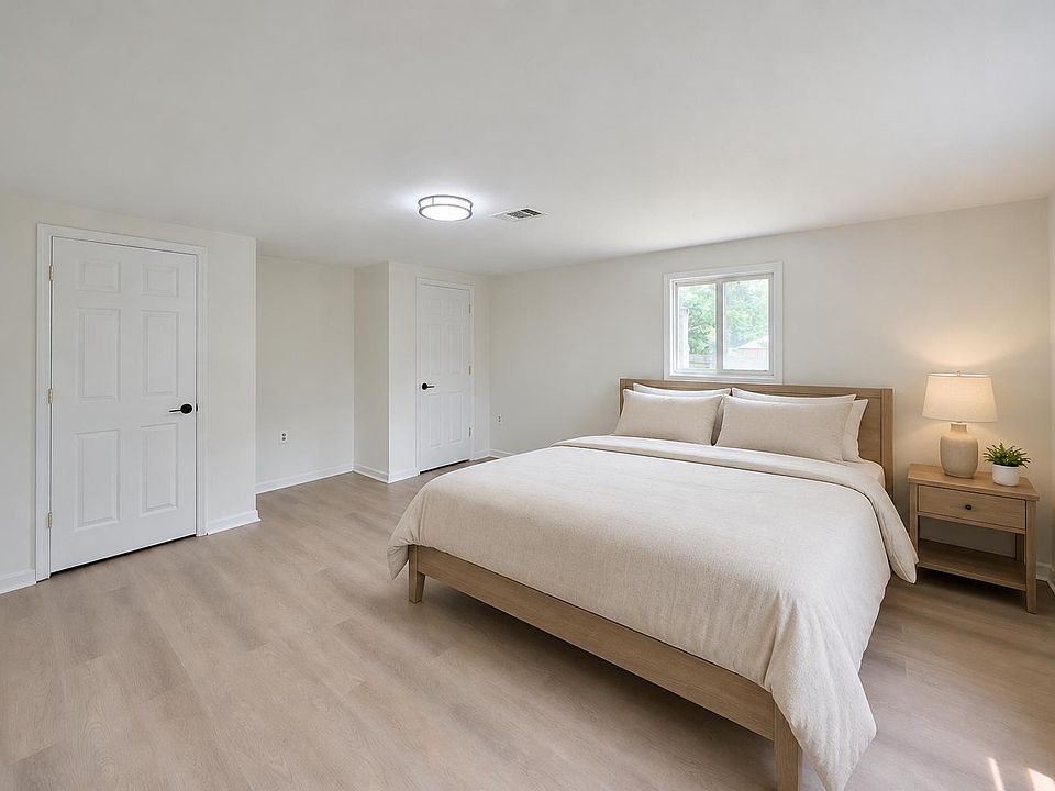 Spacious bedroom with a queen bed, wide-plank flooring, and a large closet, plus a window for natural light.