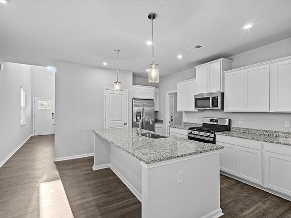 Kitchen with granite countertops, stainless steel appliances, gas stove top, dishwasher, disposal, refrigerator.