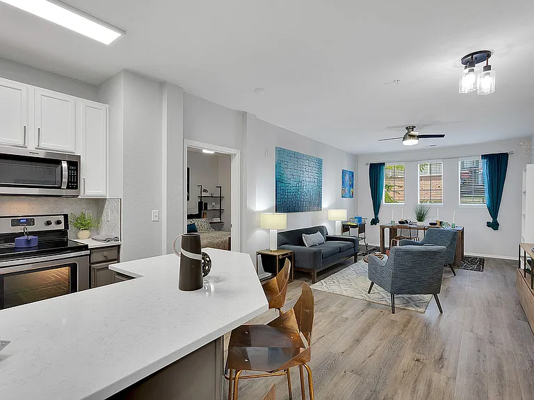 Chic open-concept apartment showcasing a modern kitchen with sleek appliances, a cozy living area with stylish decor, and abundant natural light through large windows.