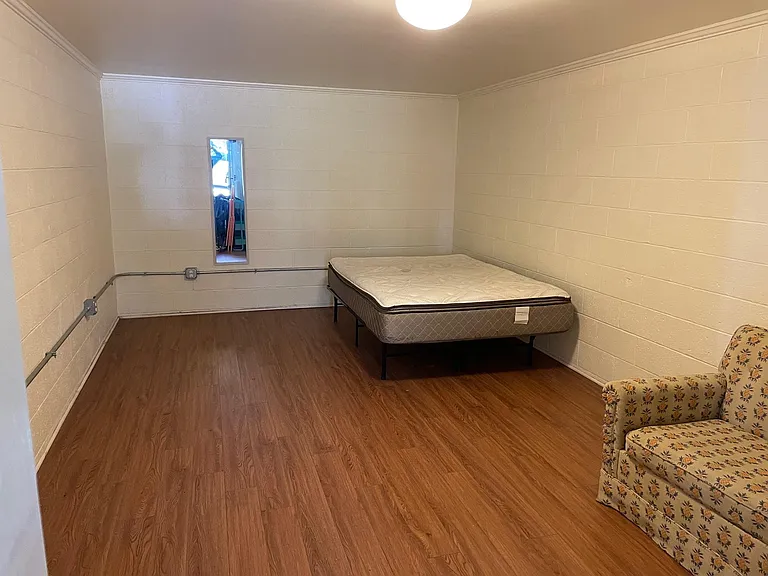 Large master bedroom with wood floors and bed and sofa (furniture will be removed)