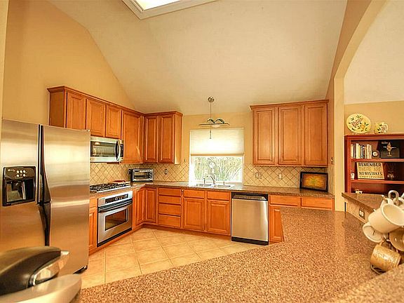 Bright open kitchen with stainless appliances & breakfast bar.