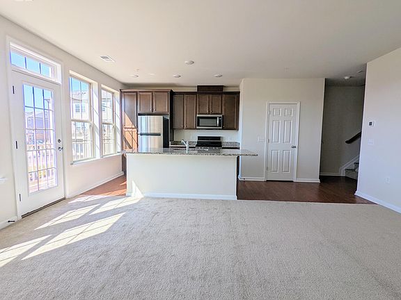 Large open kitchen design with hardwood. Bright spacious carpeted living area.