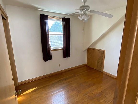 Second bedroom with hardwood floor, closet, ceiling fan and a crawl space for extra storage.