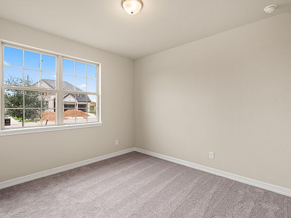 The secondary bedroom features plush carpet, fresh paint and large windows allowing plenty of natura