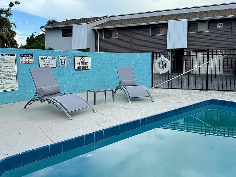 Serene apartment pool area with comfortable lounge chairs and a tranquil water view, perfect for relaxation.
