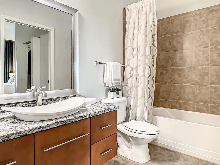 Our thoughtfully designed bathrooms boast considerable storage, fashionable framed mirrors, and spacious granite countertops with a modern bowl sink.