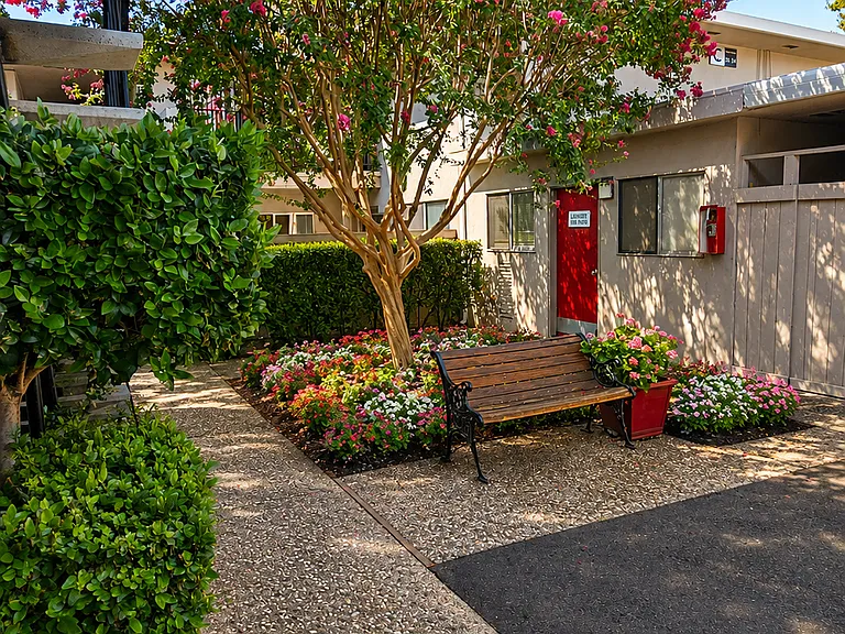 Peaceful courtyard with mature trees, colorful flowers, and relaxing seating areas.