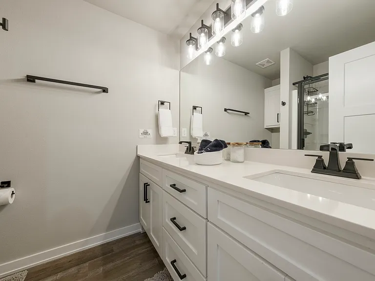 Mater bathroom has dual sinks, shower and toilet area