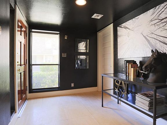 Dramatic entry with designer paint, travertine tile flooring, and recessed lighting, Full bath is located through the door to the right.