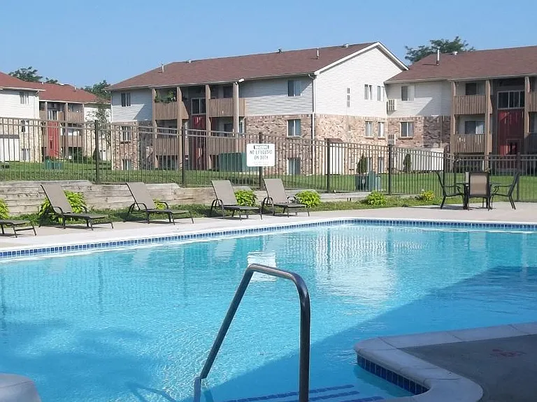Brighton Cove sparkling outdoor swimming pool with lounge chairs and tables.