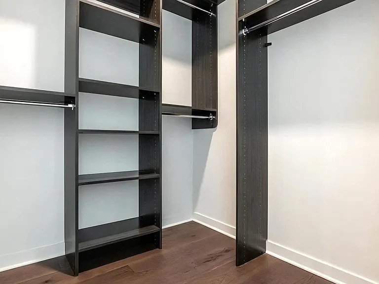 Spacious Apartment Walk-In Closet Featuring Built-In Shelves and Dark Wood Tones