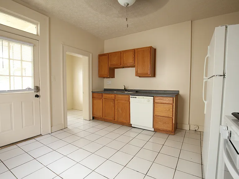 Kitchen with gas stove, dishwasher, sink with disposal. Back door to outside is on the left. A doorway to a small pantry is to the right of the back door.