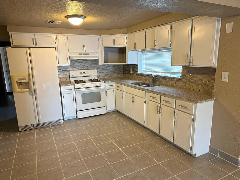Kitchen with lots of cabinets, granite countertops, stove and refrigerator.