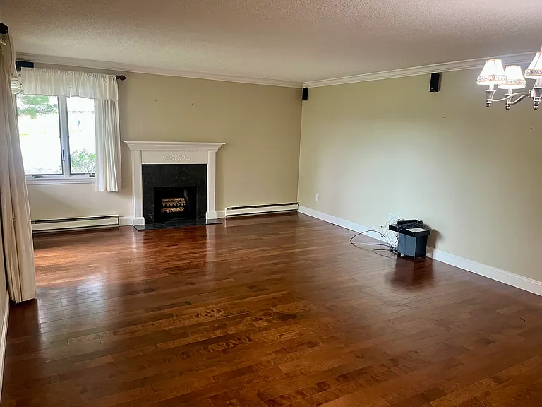 Expansive Family Room - Dining Area with hardwood floors and fireplace. Windows look out over a wild meadow, and a door opens out to the patio