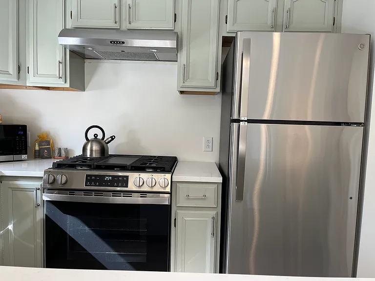 New stainless steel gas stove, refrigerator and exhaust fan with plenty of cabinet space and cookware.