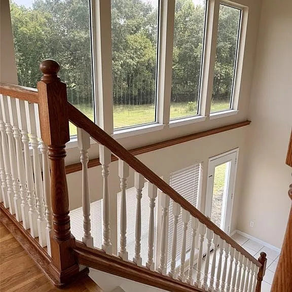 Hardwood flooring, painted balusters, wood handrails, large windows, and an exterior door