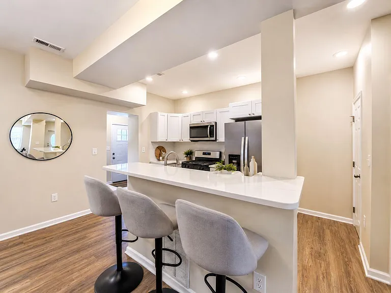 Kitchen with a large peninsula breakfast bar, shaker cabinets, and stainless-steel appliances, plus recessed lighting.
