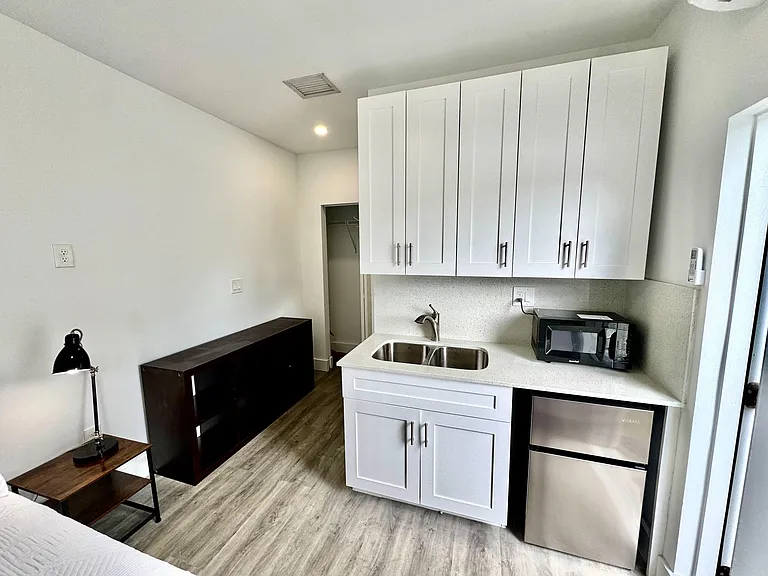 Efficient kitchenette with double sink, ample upper cabinetry, and under-counter fridgeideal for quick meals and easy storag