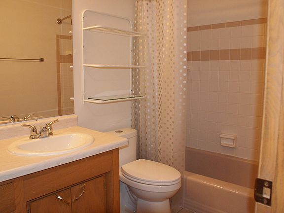 Bathroom with tiled shower over tub; Newly installed throne; vanity sink and Wall hung Mirror.