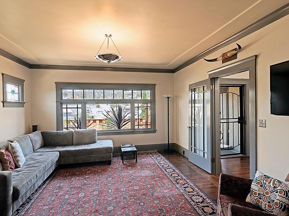 Living room has stained glass and views of the hills. Dining room (not pictured) is separated by knee-walls and flows into this space. Restored plaster detailing, period hardware