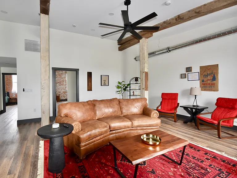 Furnished living room has a desk/work space and a smart TV. The room features ceiling spotlights that are dimmable and a ceiling fan.