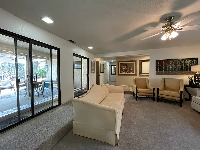 View of living room and hallway-- with lots of natural light from double pane sliding glass doors