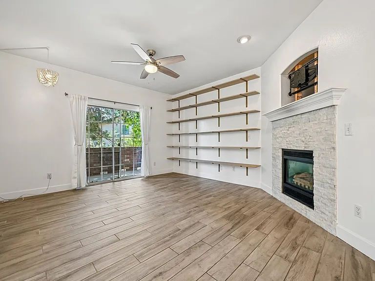 Living room, with gas fireplace, deck access and floor to ceiling bookshelves.