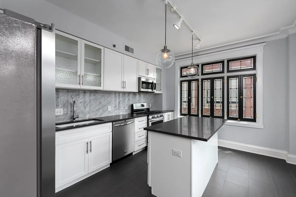 York House designer kitchen with gas stove, quartz countertops, stainless steel appliances, marble kitchen backsplash, and slate tile floor. - York House