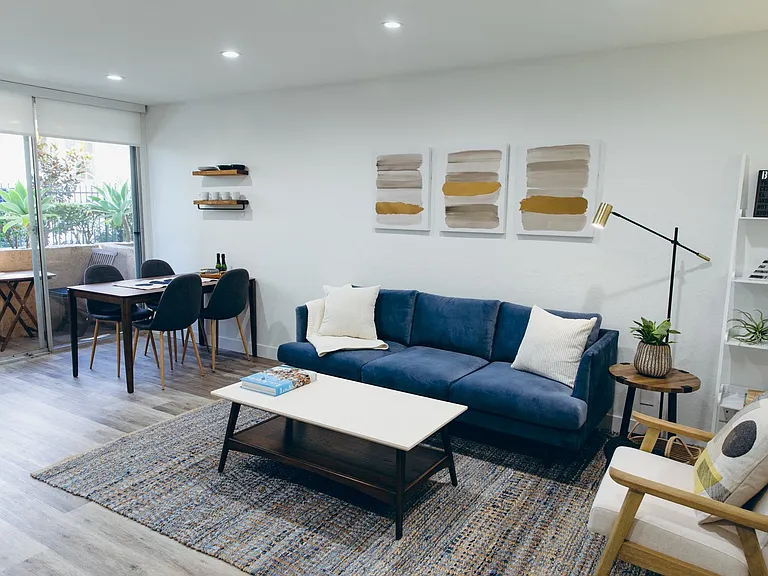 Living room with wood-inspired floors throughout, recessed lighting, dining area and balcony on the left.