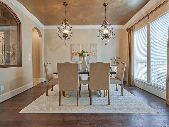 Formal dining room boasts custom painted ceiling and double chandeliers.