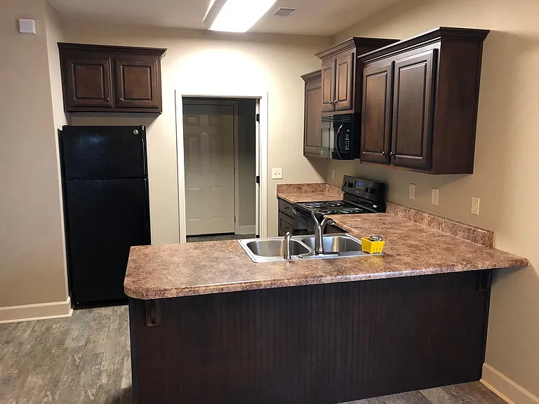 Kitchen with stained wood cabinets and bar top. All appliances included with lease.