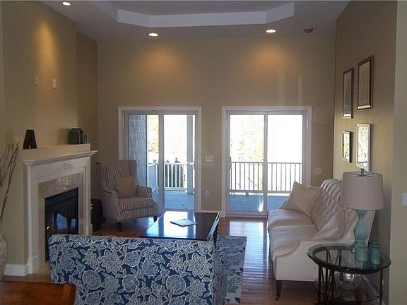 Great room with high tray ceilings, gas fireplace and mantle, double sliders to covered porch and hardwood floors.